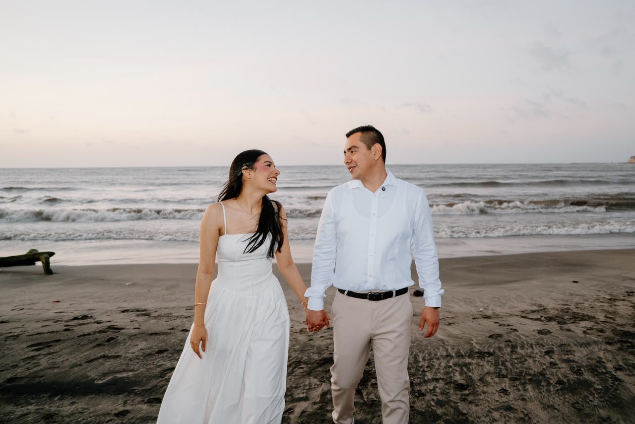 Emily y Franklin caminando de la mano junto al mar