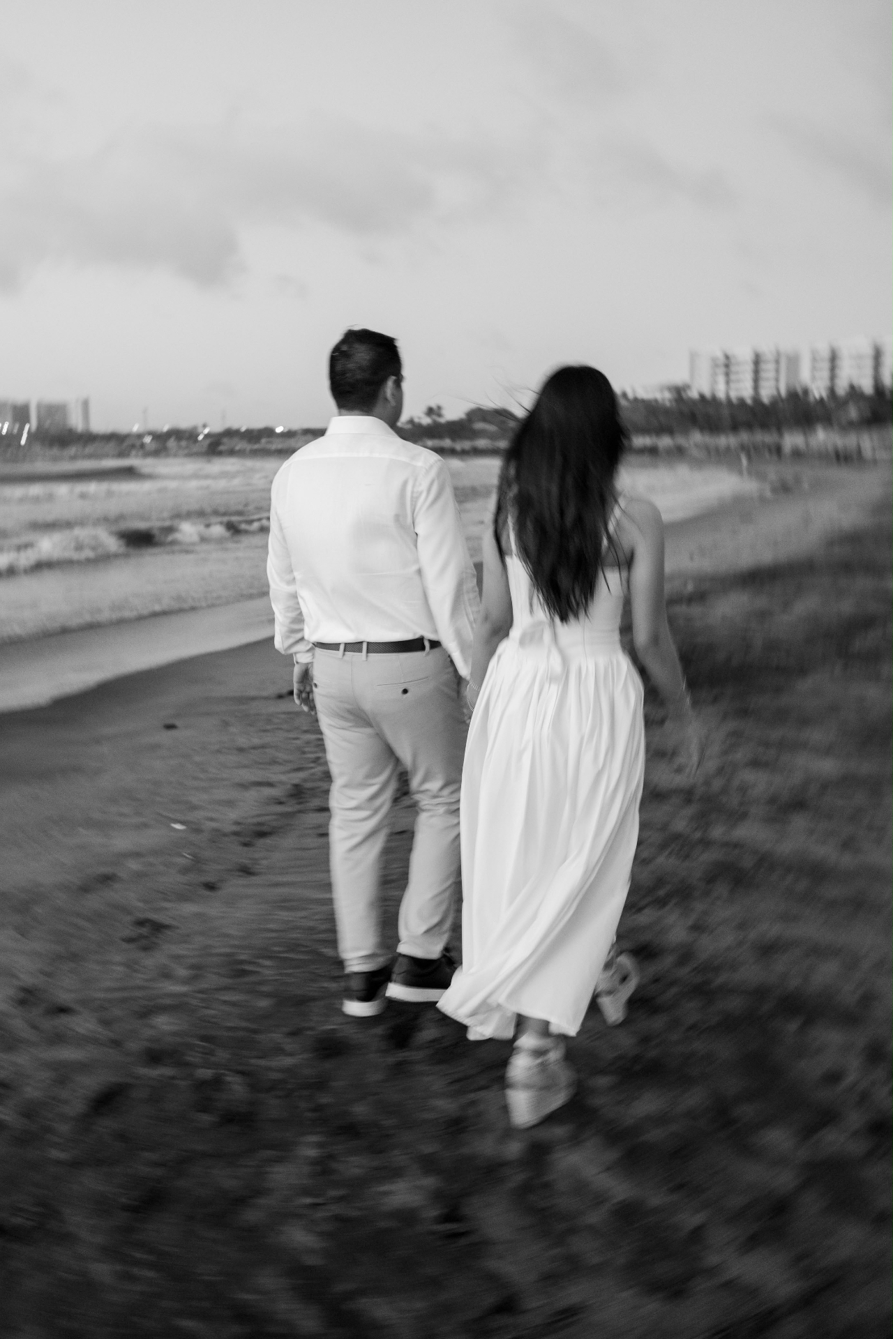 Emily y Franklin caminando por la playa, en blanco y negro