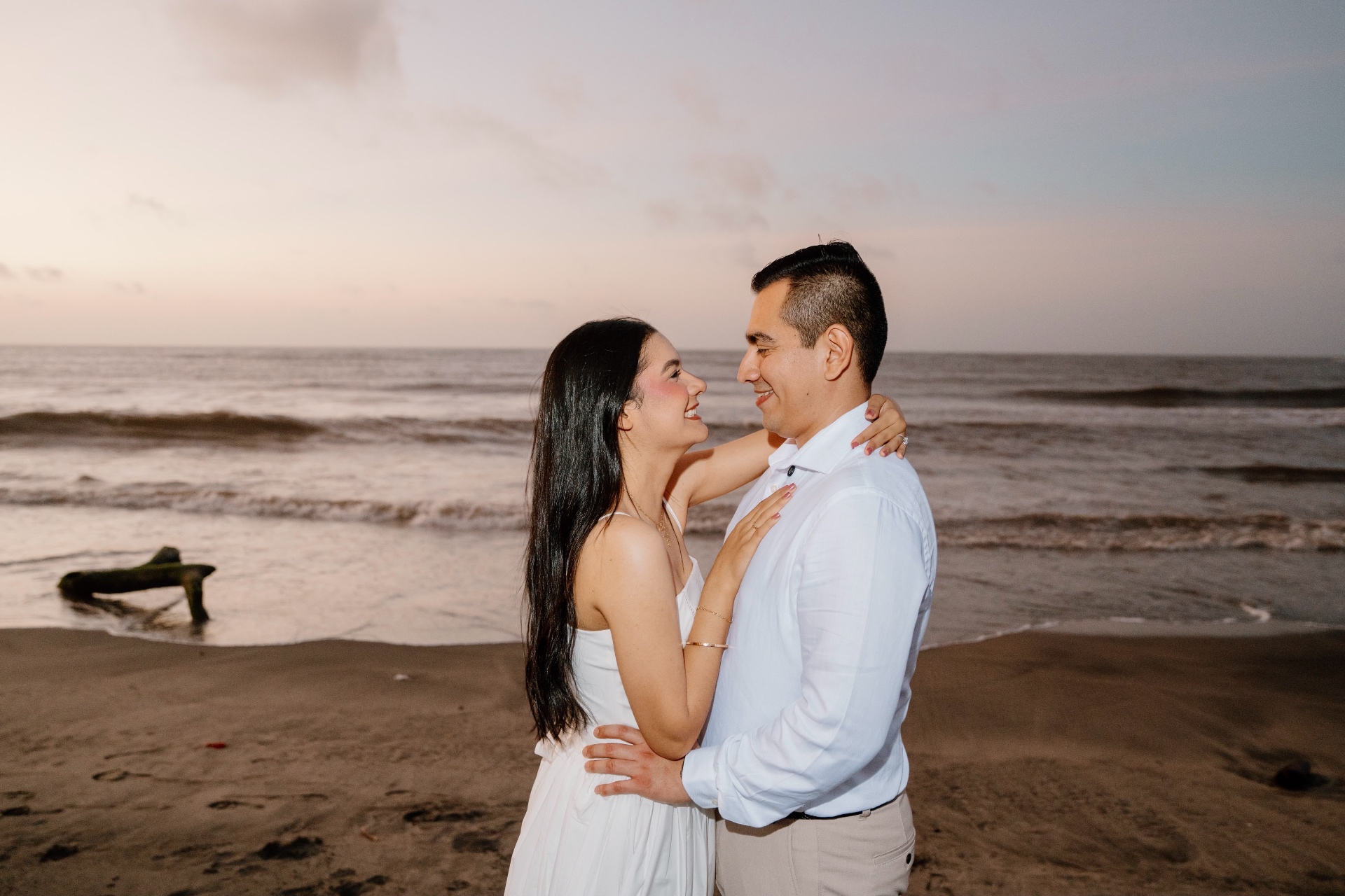 Emily y Franklin abrazados sonriendo junto al mar